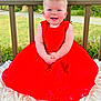 baby, blanket, cheerful, child, cute, daylight, face, flower_crown, garden, greenery, hands, happy, headband, nature, outdoor, portrait, red_dress, sitting, smile, young_child