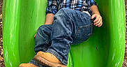 Wyatt joined the competition — help win amazing prizes! child, boy, slide, playground, green_slide, jeans, boots, plaid_shirt, outdoor, fall_leaves, smile, casual_clothing, fun, recreation, daylight, person, play, clothing, nature, happy