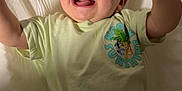 Kolsen is registered to the contest to win money with this photo: baby, bed, cartoon_print, child, clothing, crib, cute, face, happy, indoor, infant, light, pants, person, playful, raised_arms, shirt, smiling, toddler, tongue_out