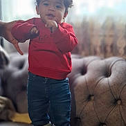 Daniel a rejoint le concours — aidez-le/la à gagner de superbes lots ! casual_clothing, child, curtains, furniture, hand, home, indoor, jeans, person, plush, red_sweatshirt, smiling, sneakers, sofa, soft_lighting, standing, support, toddler, window, young_child