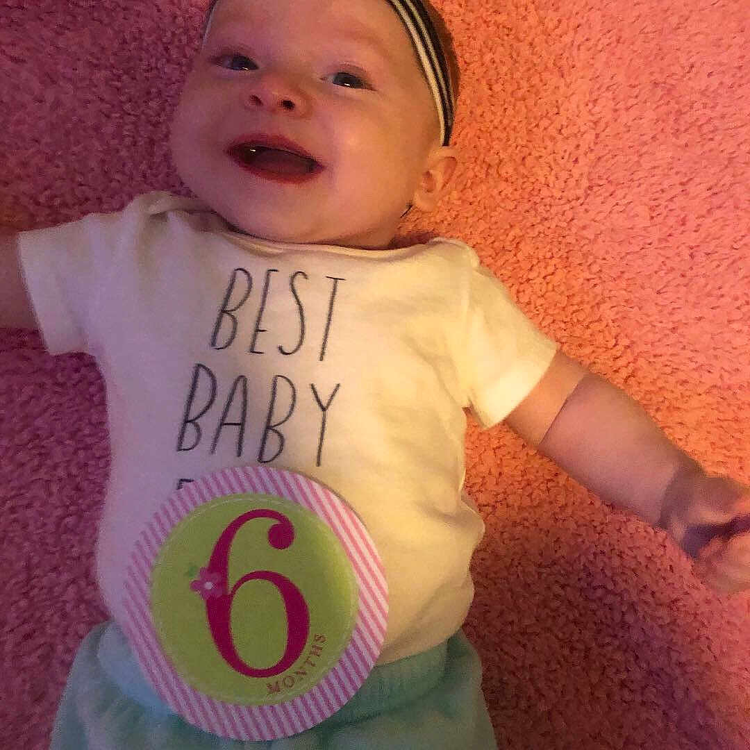 Mikala is registered to the contest to win money with this photo: baby, baby_products, baby_toddler_clothing, cheek, child, cool, facial_expression, happy, lip, number, person, pink, product, skin, sleeve, smile, t_shirt, toddler