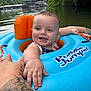 baby, child, floatie, puddle_jumper, water, lake, nature, trees, greenery, outdoor, summer, happy, smiling, tattoo, hand, infant, swimming, reaching, blue, orange