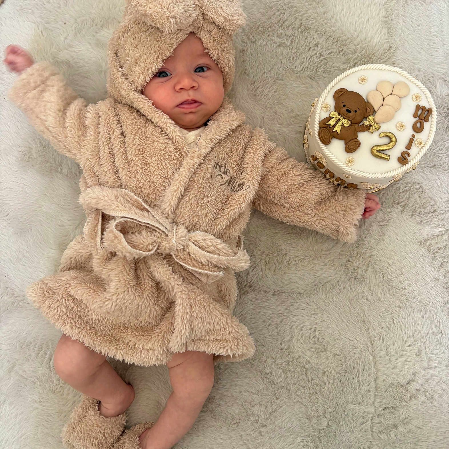 Jenna a rejoint le concours — aidez-le/la à gagner de superbes lots ! baby, robe, slippers, cake, teddy_bear, number_two, blanket, soft_texture, celebration, cute, infant, lying_down, clothing, hand, footwear, smile, portrait, indoor, child, milestone