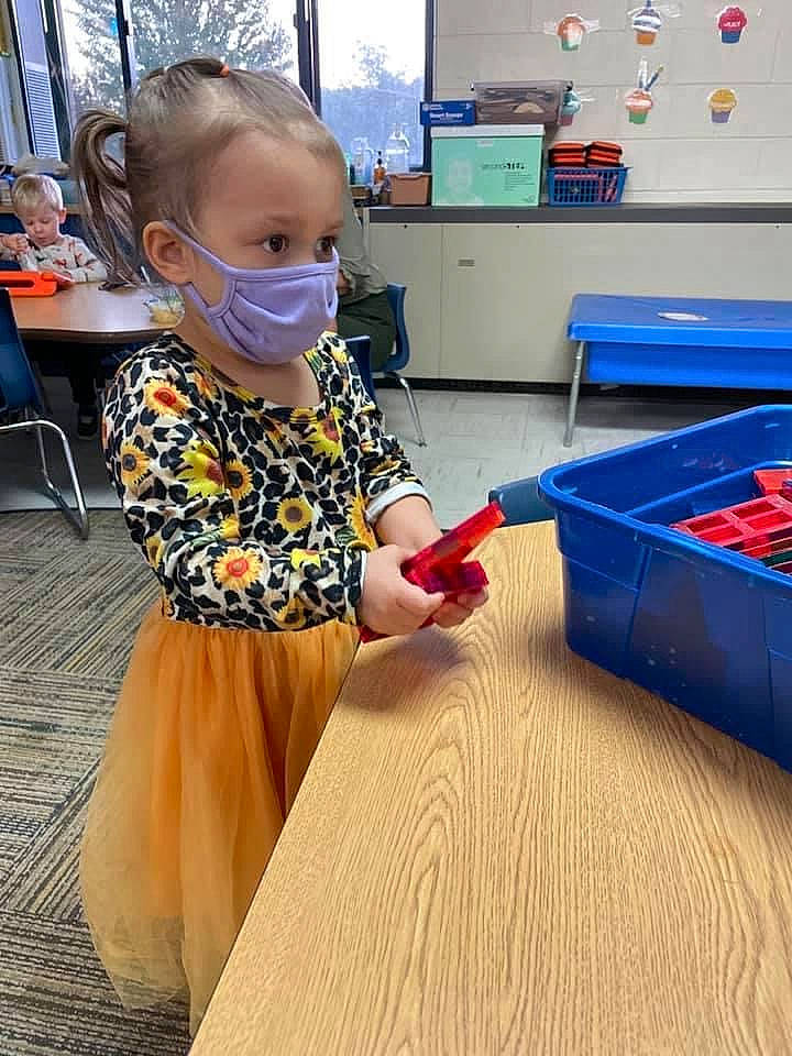 Ellie is registered to the contest to win money with this photo: chair, child, desk, electric_blue, eyewear, floor, flooring, fun, goggles, hardwood, leisure, person, play, room, standing, sunglasses, t_shirt, table, toddler, varnish
