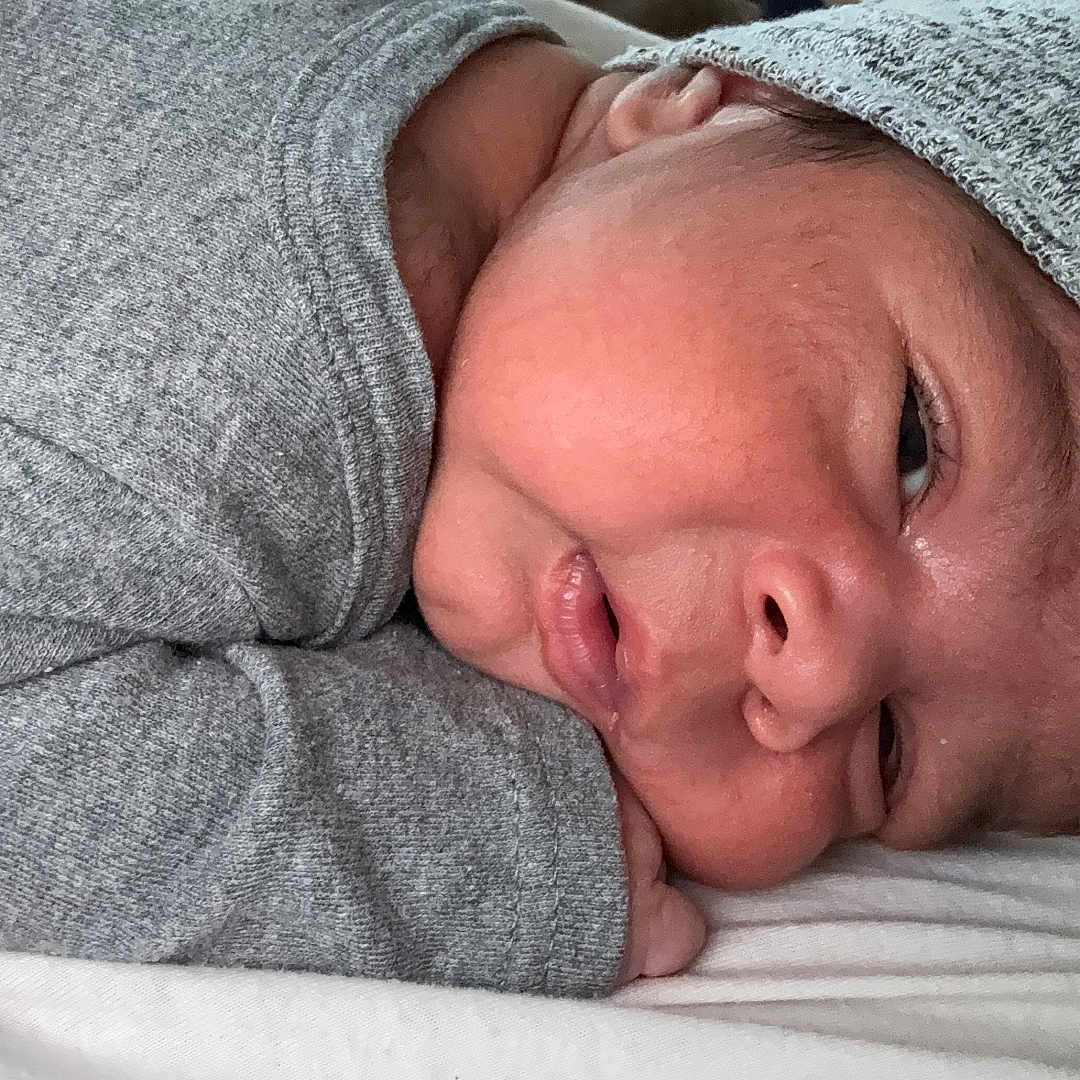 Jose is registered to the contest to win money with this photo: newborn, baby, infant, sleeping, grey_clothing, hat, closeup, face, skin, resting, cute, cozy, portrait, child, young, peaceful, soft, blanket, lying_down, indoors