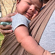 Jose joined the competition — help win amazing prizes! baby, infant, child, face, skin, hand, arm, baby_carrier, fabric, outdoor, sunlight, person, close_up, happy, smile, holding, casual_clothing, texture, parent, affection