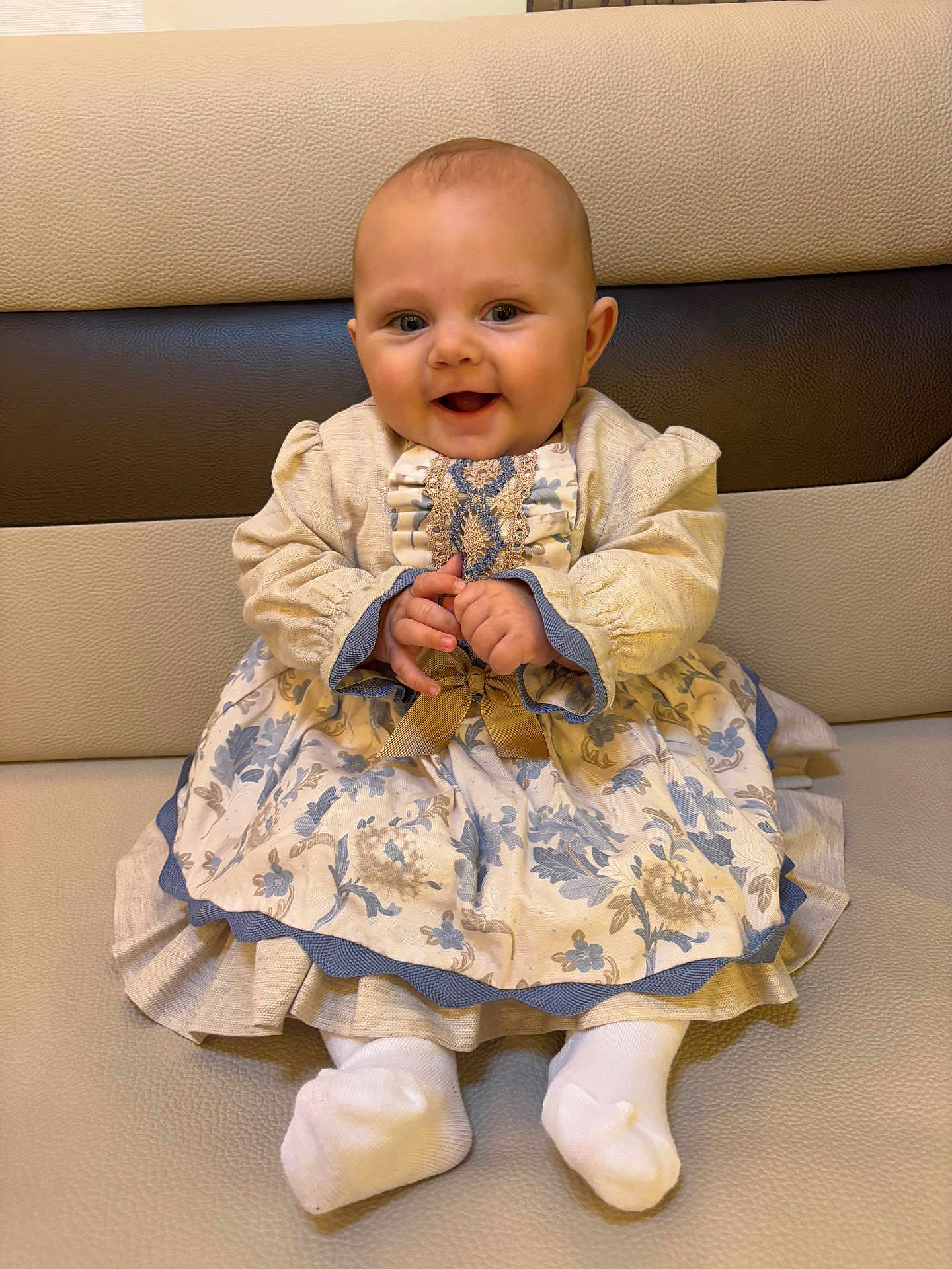 Asaël participe au concours pour gagner de l'argent avec cette photo : baby, child, smile, dress, floral_pattern, sitting, couch, cushion, happy, cute, portrait, indoors, sock, hands, head, face, person, clothing, furniture, infant