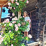 Agathe participe au concours pour gagner de l'argent avec cette photo : child, girl, flowers, roses, glasses, white_dress, wooden_porch, log_cabin, greenery, plants, outdoor, sunlight, nature, smiling, summer, leaves, wood, standing, happy, portrait