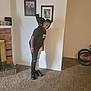 bicycle, black_cat, boy, carpet, carpeted_floor, casual_clothing, cat, fireplace, framed_photos, furniture, happy, home_interior, human, indoor, light_switch, pet, portrait, smiling, sneakers, wall
