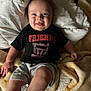 Cooper is registered to the contest to win money with this photo: baby, child, smiling, blanket, quilt, tshirt, shorts, person, happy, face, tongue, indoor, cute, infant, clothing, soft, comfort, lying_down, skin, head