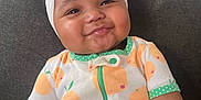 Savani Sage is registered to the contest to win money with this photo: baby, child, smiling, headband, bow, onesie, orange_pattern, couch, indoor, face, cute, cheeks, infant, sitting, happy, person, clothing, textile, portrait, home