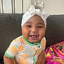 Savani Sage joined the competition — help win amazing prizes! baby, child, smiling, headband, bow, onesie, fruit_print, orange, couch, blanket, pink, happy, tongue_out, infant, cute, indoor, person, portrait, seated, clothing