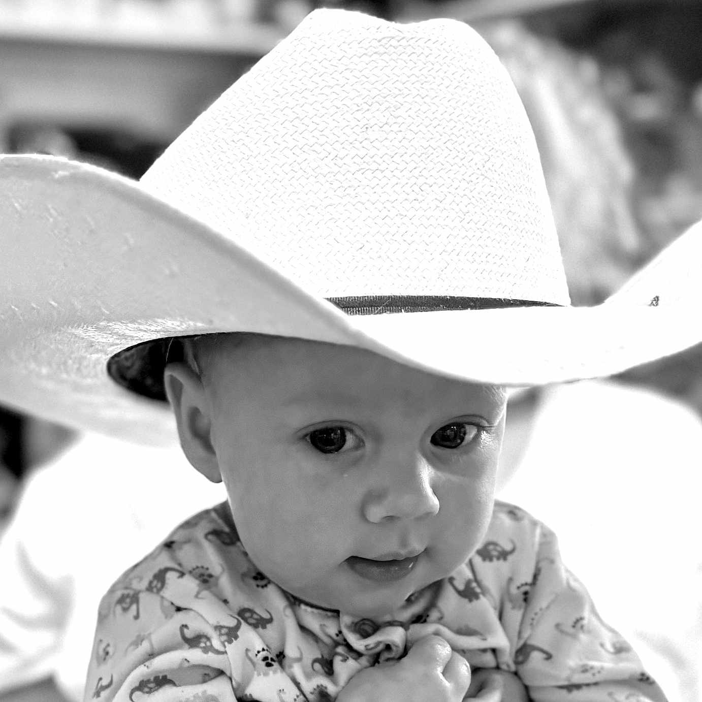 Wesley is registered to the contest to win money with this photo: baby, child, cowboy_hat, hat, cute, portrait, infant, face, eyes, clothing, pattern, indoor, soft_focus, black_and_white, expression, person, young, headwear, adorable, closeup