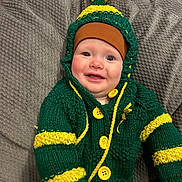 Leo is registered to the contest to win money with this photo: baby, infant, child, smile, happy, knit_hat, pom_pom, sweater, cardigan, green_sweater, yellow_buttons, cozy, blanket, couch, portrait, rosy_cheeks, blue_eyes, sitting, adorable, closeup