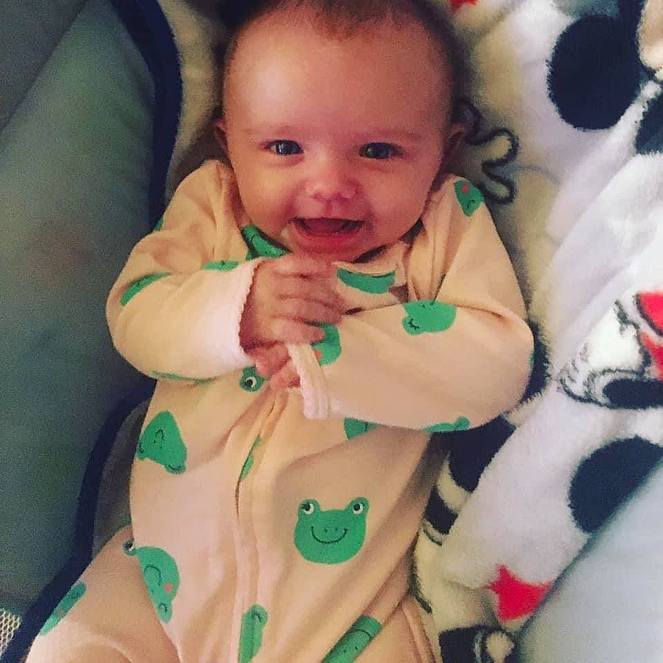 Malia is registered to the contest to win money with this photo: arm, baby, baby_toddler_clothing, cheek, comfort, eye, face, finger, gesture, green, hand, head, human_body, neck, nose, person, photograph, skin, sleeve, smile