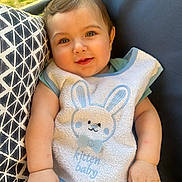 Zain is registered to the contest to win money with this photo: baby, child, bib, bunny, cute, smiling, face, hand, striped_pants, pillow, pattern, chair, outdoor, grass, sunlight, happy, infant, portrait, clothing, person
