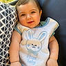 baby, bib, bunny, chair, child, clothing, cute, face, grass, hand, happy, infant, outdoor, pattern, person, pillow, portrait, smiling, striped_pants, sunlight