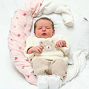 Ayla a rejoint le concours — aidez-le/la à gagner de superbes lots ! baby, newborn, infant, knitwear, booties, pillow, strawberry_pattern, white_background, cozy, cute, sleepy, soft_texture, child, portrait, resting, small_hands, cuddly, warm, sleepwear, blanket