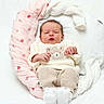 baby, newborn, infant, cute, cozy, knitwear, bear_face, pink_cushion, strawberry_pattern, blanket, soft, white_background, sleepy, small_hands, white_socks, portrait, child, resting, indoors, comfortable