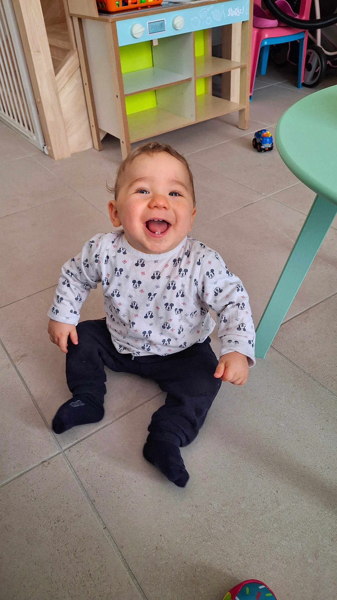 Tyrone participe au concours pour gagner de l'argent avec cette photo : baby, child, smiling, sitting, indoor, floor, toy, table, furniture, happiness, mickey_mouse, clothing, person, cute, playroom, pants, socks, joyful, young, home