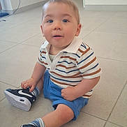 Tyrone participe au concours pour gagner de l'argent avec cette photo : baby, blue_shorts, casual_clothing, child, curious, cute, floor, home, indoor, light, neutral_background, person, portrait, sitting, sneakers, socks, striped_shirt, tiles, toddler, young_child