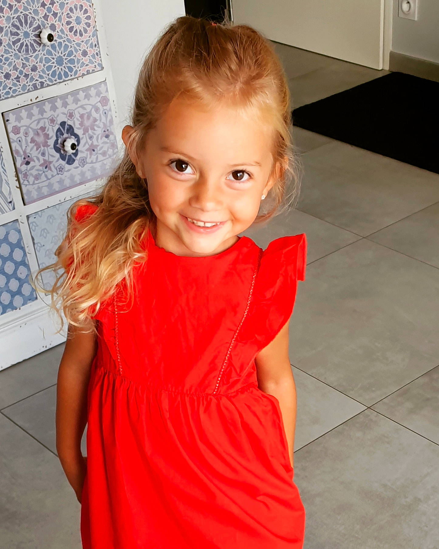 Kimlie participe au concours pour gagner de l'argent avec cette photo : arm, blond, child, child_model, clothing, dress, flooring, hair, hairstyle, joint, joy, long_hair, neck, person, shoulder, smile, standing, toddler