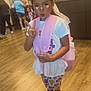 child, girl, indoor, peace_sign, backpack, colorful_clothing, shoes, flooring, people, pout, digital_filter, eyelashes, butterflies, wood_floor, casual_wear, standing, playful, room, light, portrait