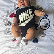 Amari is registered to the contest to win money with this photo: apparel, baby, baby_boy, blanket, child, clothing, cute, fashion, footwear, hat, indoors, infant, lying_down, nike, numbers, person, portrait, smiling, sneakers, socks