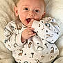 baby, infant, child, smiling, cute, dinosaur_print, sweater, green_pants, hand_in_mouth, fluffy_blanket, cozy, happy, portrait, indoors, closeup, skin, face, eyes, person, young