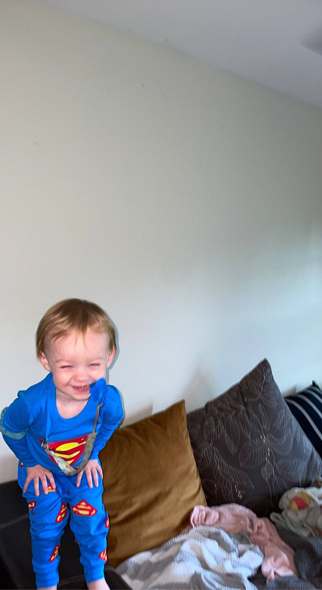 Hendrix is registered to the contest to win money with this photo: baby_toddler_clothing, child, comfort, couch, electric_blue, flooring, fun, happy, head, joy, leisure, linens, living_room, person, pillow, sitting, sleeve, smile, t_shirt, throw_pillow