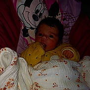 Noèline participe au concours pour gagner de l'argent avec cette photo : baby, infant, child, blanket, pillow, minnie_mouse, cartoon, bedding, cozy, hand, finger, eyes, hair, face, portrait, indoors, yellow_clothing, floral_pattern, comforter, nap_time