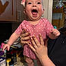Piper joined the competition — help win amazing prizes! baby, infant, pink_onesie, polka_dot, smiling, happy, person_holding, manicure, nails, kitchen, cabinet, countertop, nutrition_facts, bottle, ceiling_fan, lights, indoor, portrait, hand, cheerful