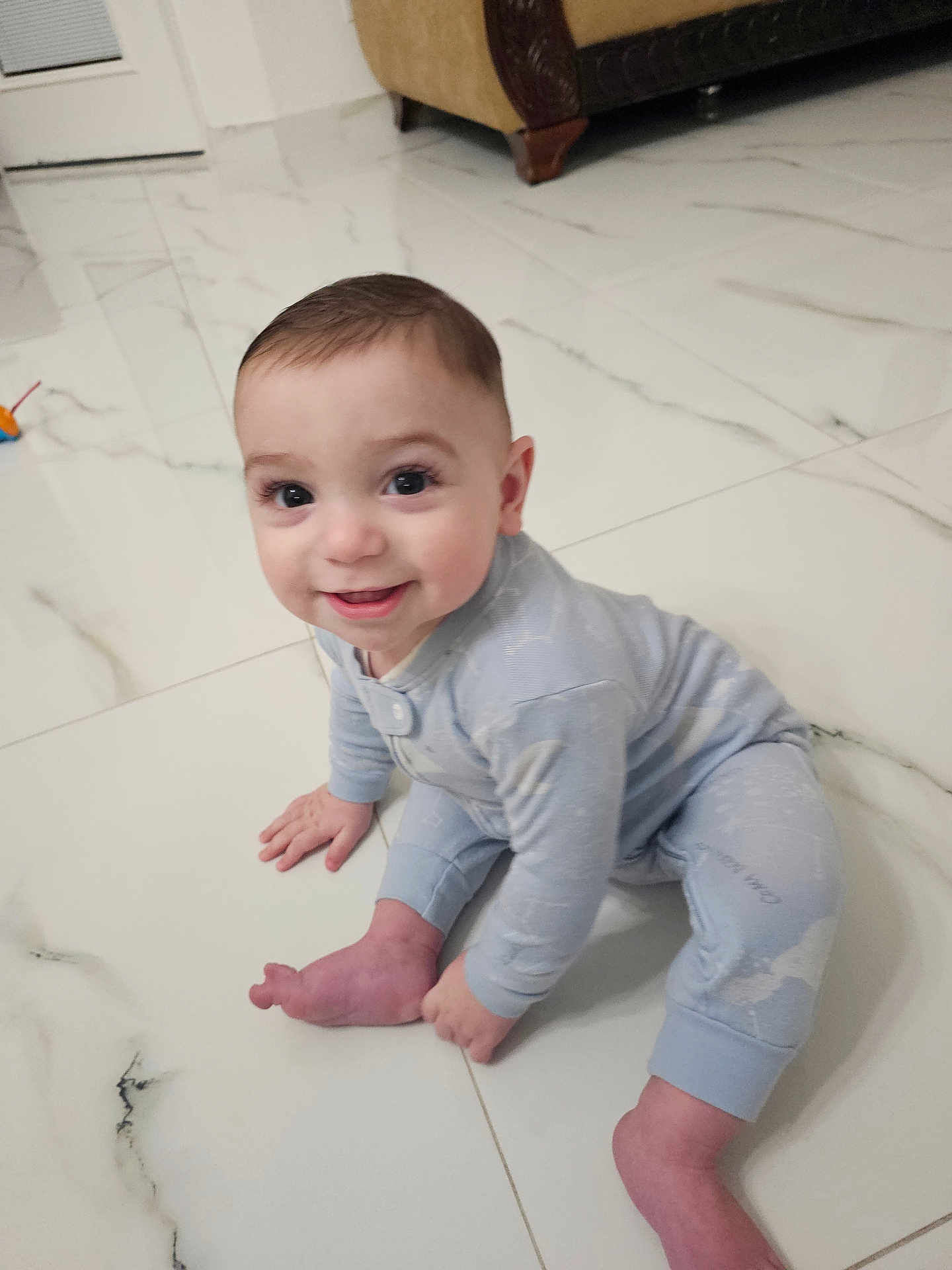 Fidel is registered to the contest to win money with this photo: baby, child, smiling, crawling, pajamas, floor, tile, indoor, living_room, cute, happy, infant, person, young_child, home, bright, eyes, hand, foot, head