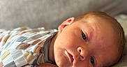 Colter joined the competition — help win amazing prizes! baby, infant, face, closeup, lying_down, patterned_clothing, soft_surface, skin, head, young_child, portrait, calm, indoors, sleepy, newborn, cute, child, human, resting, expression