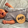 baby, newborn, infant, yawning, blanket, blue_clothing, wooden_sign, one_month, sleepy, cute, lying_down, soft_texture, knitted_blanket, child, portrait, indoors, peaceful, small_hands, buttoned_clothing, resting