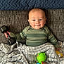 baby, bed, blanket, clothing, couch, cushion, electricaldevice, face, furniture, happy, head, homedecor, microphone, pants, person, photography, portrait, quilt, smile, toy