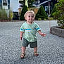 toddler, child, walking, outdoor, gravel, greenery, house, shorts, tshirt, sandals, curly_hair, daylight, sidewalk, summer, cute, portrait, person, happy, nature, background