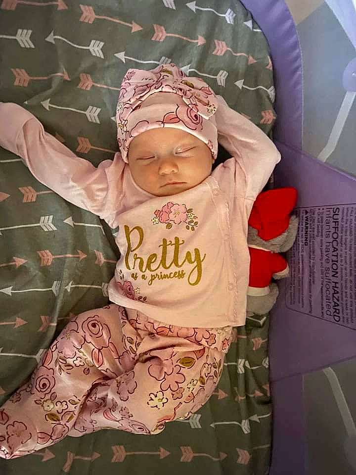 Dahlia is registered to the contest to win money with this photo: baby, baby_products, baby_toddler_clothing, beanie, cap, child, comfort, eyewear, fun, glasses, happy, headwear, magenta, pattern, person, pink, room, sitting, sleeve, t_shirt