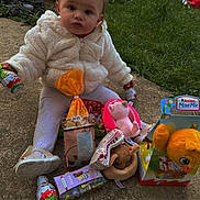 Gloria participe au concours pour gagner de l'argent avec cette photo : toddler, child, outdoor, grass, toy, plush_toy, candy, snack, jacket, white_clothing, sitting, concrete, cute, face, person, holding, easter, celebration, gift, happy