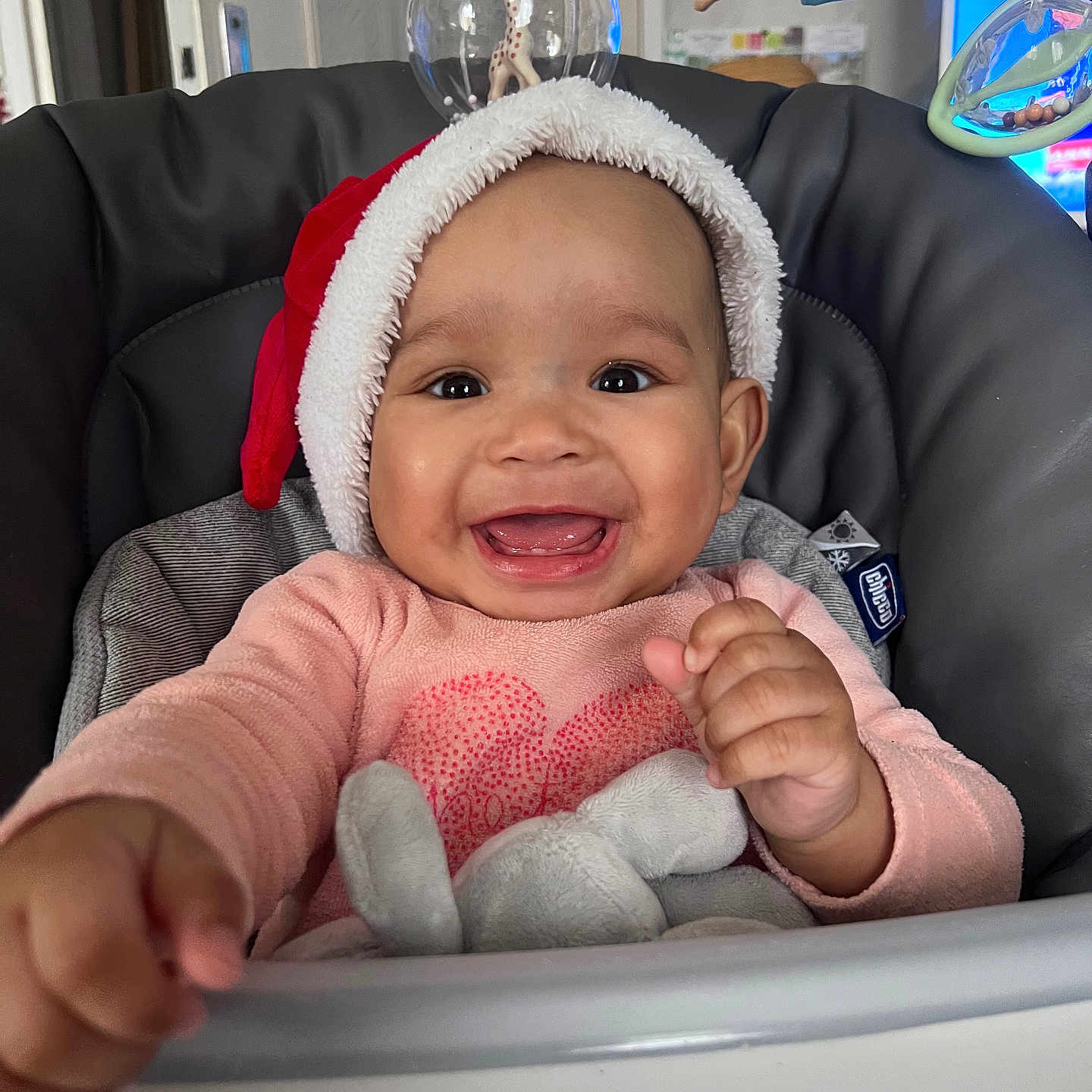Lylia a rejoint le concours — aidez-le/la à gagner de superbes lots ! baby, cheerful, child, clothing, cute, expression, face, festive, hand, happy, high_chair, holiday, indoors, infant, person, portrait, santa_hat, seat, smiling, toy