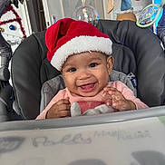 Lylia participe au concours pour gagner de l'argent avec cette photo : baby, child, smiling, santa_hat, baby_seat, toy, indoors, happy, cute, holiday, festive, clothing, face, person, seat, infant, cheerful, red, pink, decorations