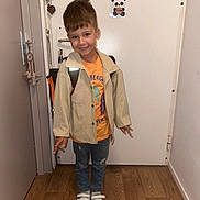 Miguel a rejoint le concours — aidez-le/la à gagner de superbes lots ! child, boy, smiling, standing, backpack, casual_clothing, jeans, sneakers, indoor, door, wooden_floor, panda_drawing, playful, happy, portrait, casual, light_jacket, home, young, cute