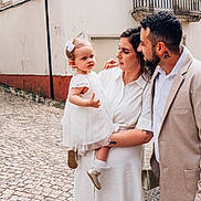 Alma a rejoint le concours — aidez-le/la à gagner de superbes lots ! child, toddler, woman, man, family, street, cobblestone, white_dress, holding, outdoor, urban, building, smile, tattoo, hair_bow, mother, father, portrait, casual, love