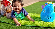 Joseph is registered to the contest to win money with this photo: blue_bunny_bag, casual_clothing, child, crawling, curly_hair, cute, daylight, gift_bag, grass, green_mat, happy, outdoor, park, playful, red_bow, short_sleeves, smile, sunlight, toddler, toy