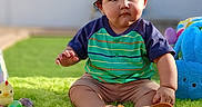 Joseph joined the competition — help win amazing prizes! toddler, child, bunny_ears, outdoor, grass, toy, plush, shirt, sitting, cute, sunny, playful, green_rug, baby, portrait, daylight, curious, casual_clothing, footwear, backyard
