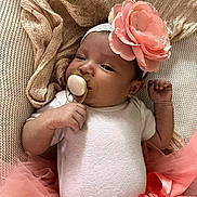 Naomi joined the competition — help win amazing prizes! baby, infant, pacifier, headband, flower, pink, tutu, onesie, blanket, lying_down, cute, newborn, soft_texture, sleepy, hand, portrait, indoors, child, adorable, resting