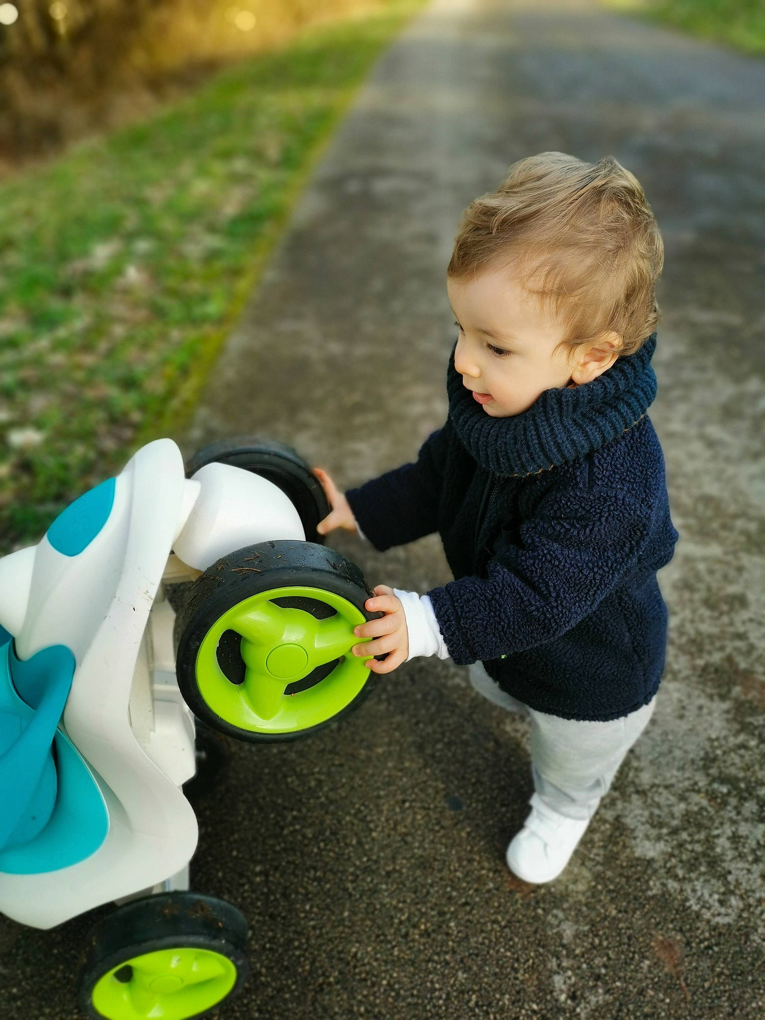 Gaspard a rejoint le concours — aidez-le/la à gagner de superbes lots ! asphalt, baby, baby_toddler_clothing, child, fun, grass, green, happy, lawn, leisure, people_in_nature, person, personal_protective_equipment, plant, recreation, shoe, sitting, sneakers, toddler, toy