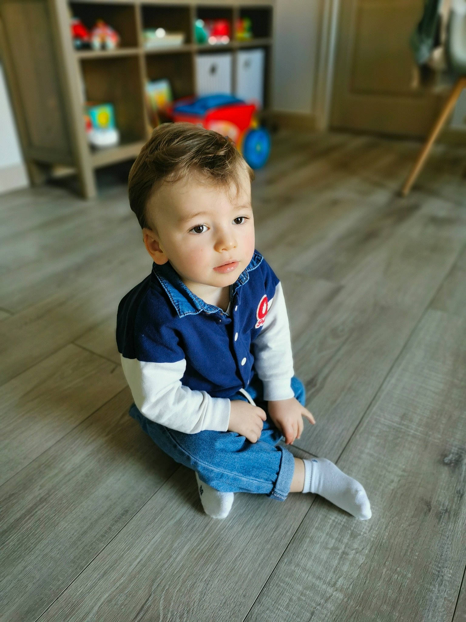Gaspard a rejoint le concours — aidez-le/la à gagner de superbes lots ! baby, baby_toddler_clothing, child, electric_blue, floor, flooring, foot, fun, happy, hardwood, laminate_flooring, person, picture_frame, plank, sitting, skin, toddler, varnish, wood, wood_flooring