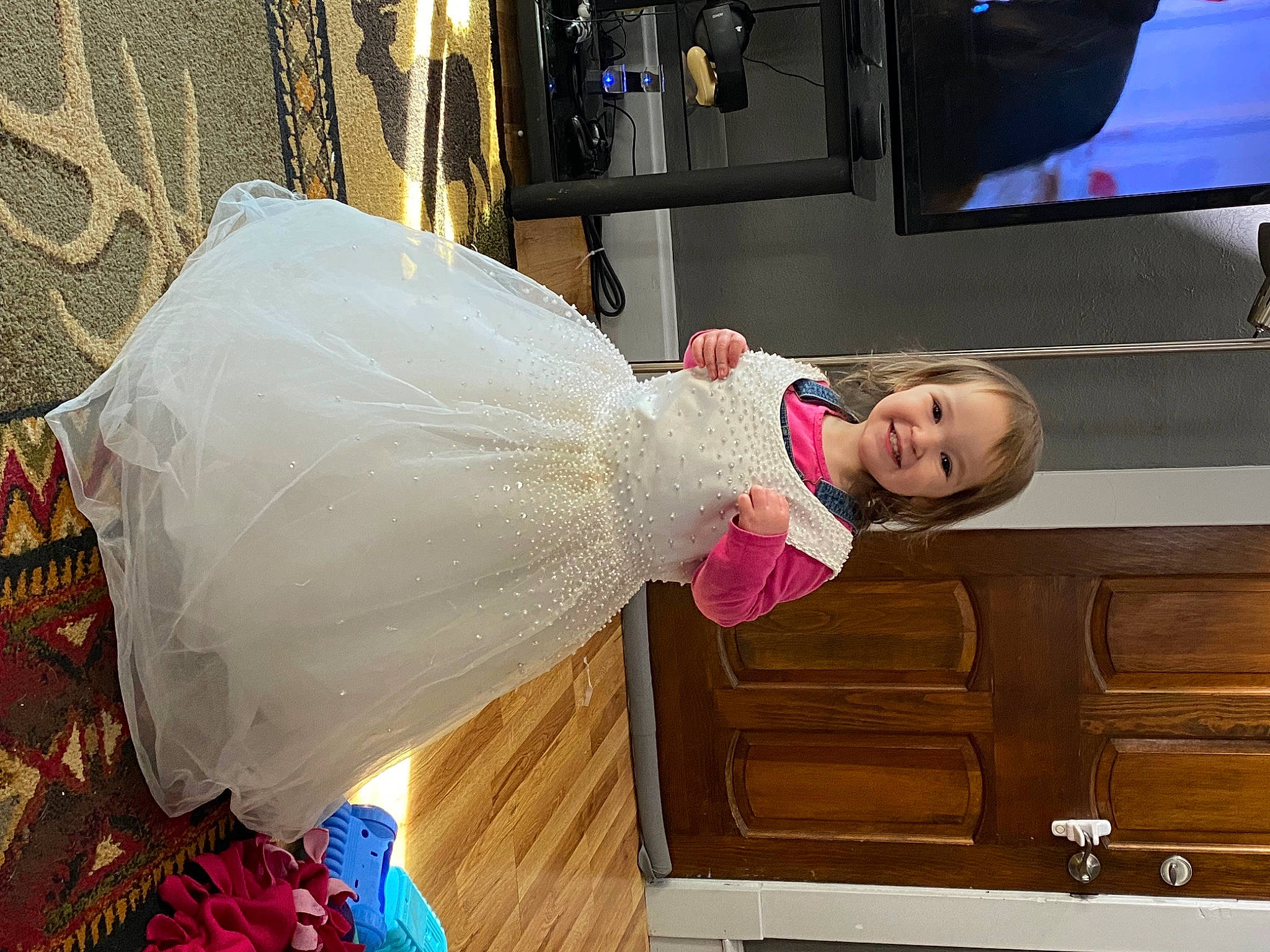 Espen is registered to the contest to win money with this photo: bridal_clothing, drawer, event, fashion_design, flooring, formal_wear, fun, gown, happy, hardwood, joy, magenta, person, product, room, smile, snapshot, television, television_set, toddler