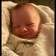 Lucas joined the competition — help win amazing prizes! baby, infant, blanket, smile, sleepy, cozy, face, clothing, cute, newborn, soft, warm, happy, resting, child, indoors, person, portrait, snuggled, sleep